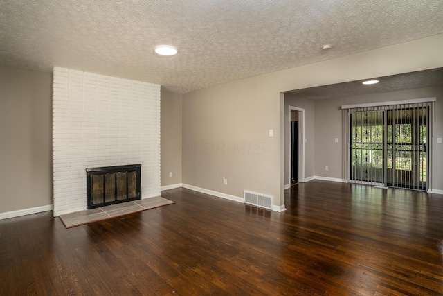 unfurnished living room with a fireplace, a textured ceiling, and dark hardwood / wood-style floors