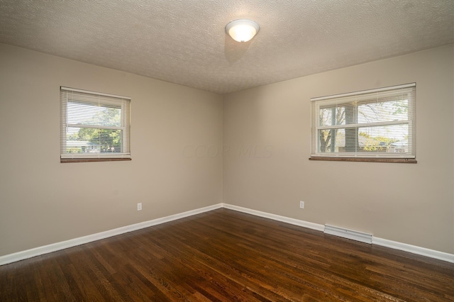 empty room with dark hardwood / wood-style floors and a textured ceiling