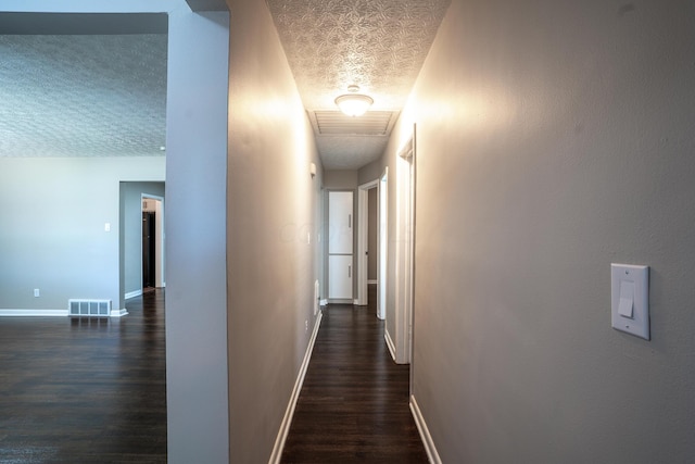 corridor featuring a textured ceiling and dark wood-type flooring