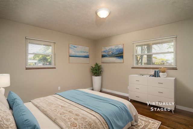 bedroom with dark hardwood / wood-style floors, a textured ceiling, and multiple windows