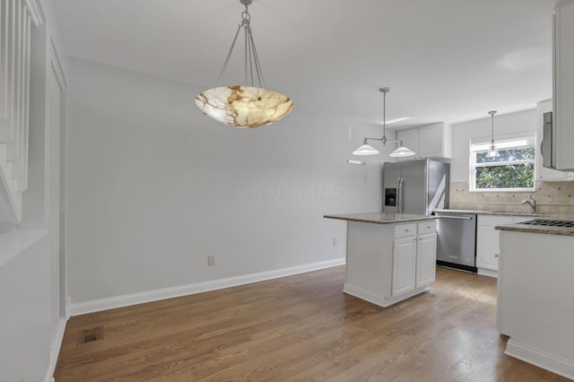 kitchen with white cabinets, a kitchen island, decorative light fixtures, and appliances with stainless steel finishes