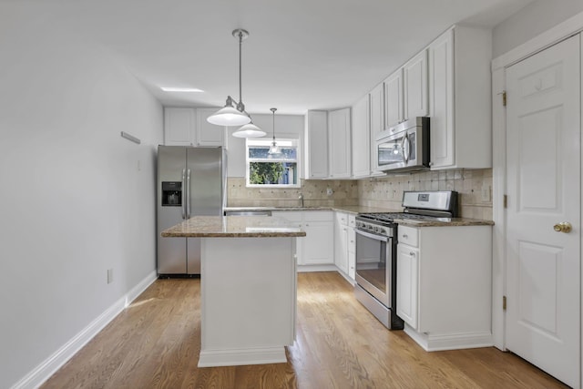 kitchen featuring a center island, white cabinets, light hardwood / wood-style flooring, appliances with stainless steel finishes, and decorative light fixtures