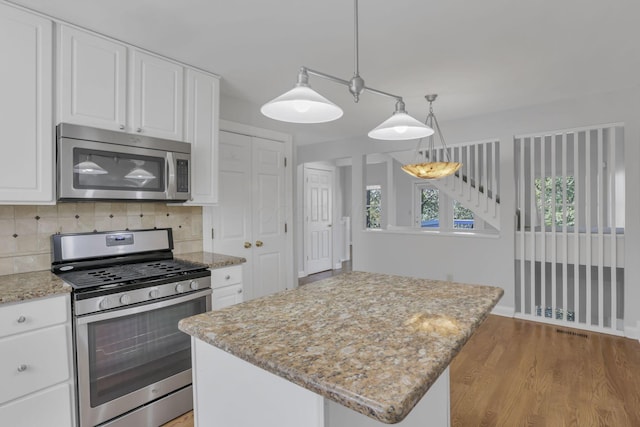 kitchen with backsplash, white cabinets, stainless steel appliances, and a kitchen island