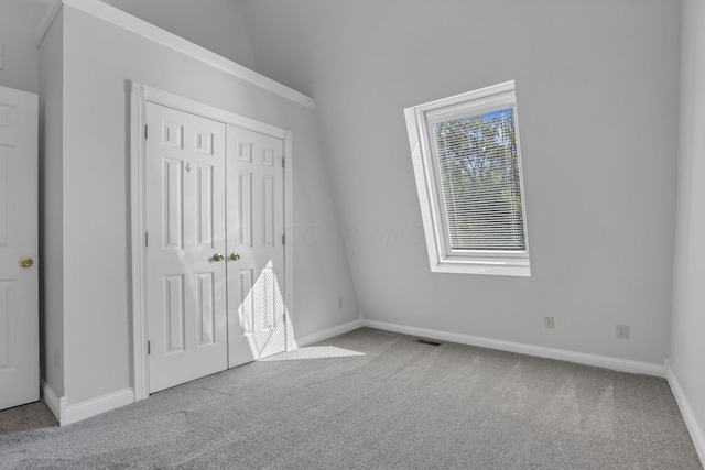 unfurnished bedroom featuring a closet, light colored carpet, and lofted ceiling