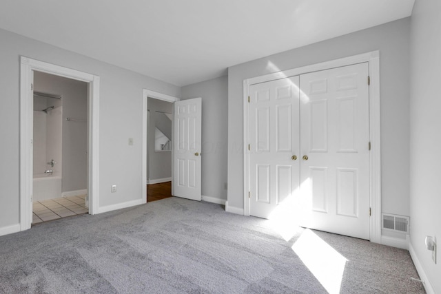 unfurnished bedroom with connected bathroom, light colored carpet, and a closet