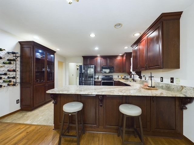 kitchen with sink, a kitchen breakfast bar, kitchen peninsula, and stainless steel refrigerator with ice dispenser