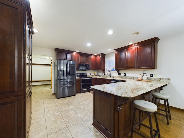 kitchen with a breakfast bar, sink, light stone counters, kitchen peninsula, and stainless steel appliances