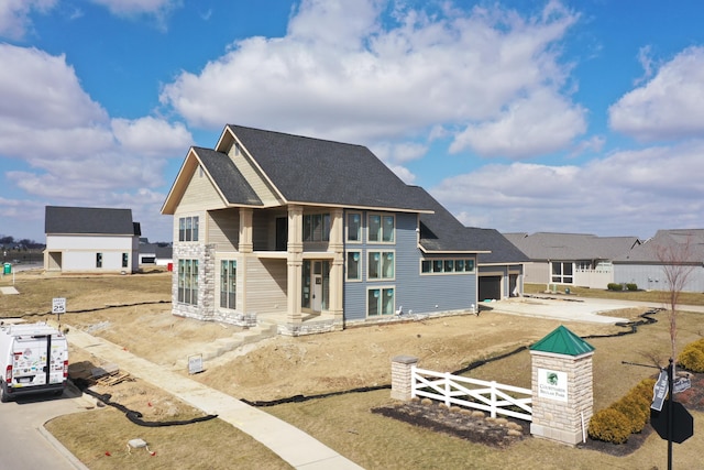 exterior space with driveway, a residential view, fence, and roof with shingles