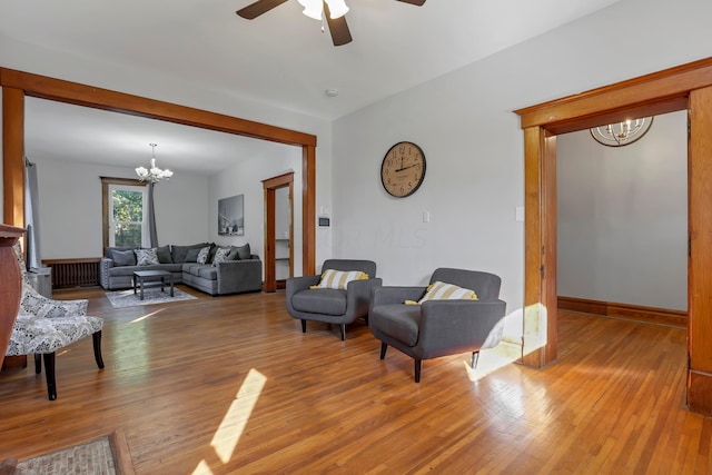 living room with wood-type flooring and ceiling fan with notable chandelier