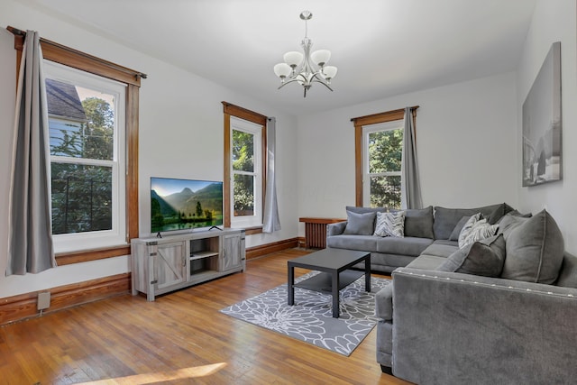 living room with an inviting chandelier, a wealth of natural light, and light hardwood / wood-style flooring