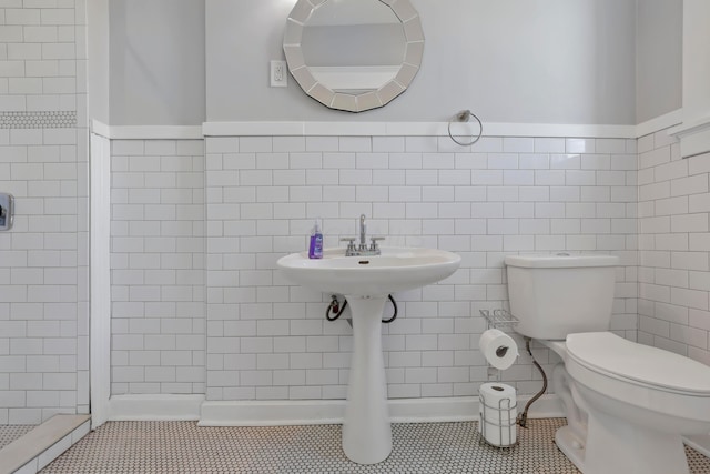 bathroom with tile patterned floors, toilet, and tile walls