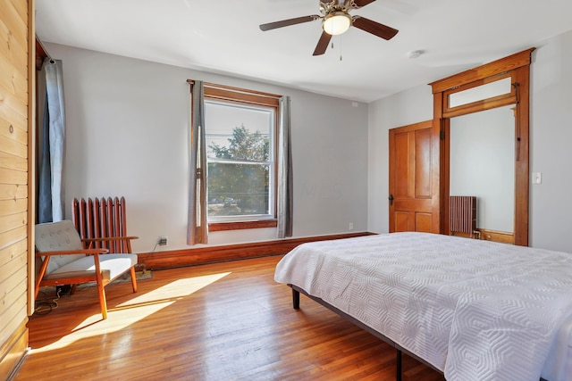 bedroom with ceiling fan, radiator heating unit, and light wood-type flooring