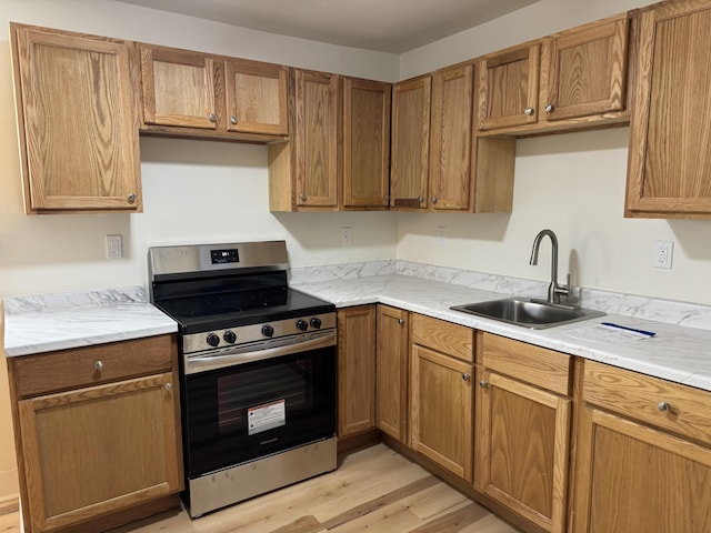 kitchen featuring light hardwood / wood-style flooring, stainless steel stove, and sink