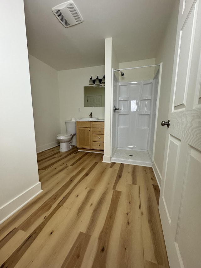 bathroom with toilet, hardwood / wood-style floors, vanity, and walk in shower