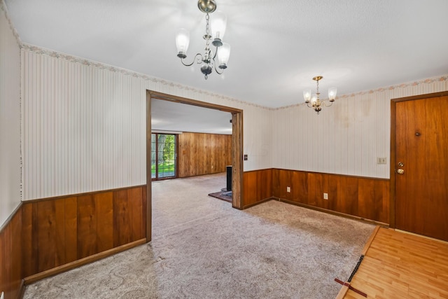 unfurnished room featuring hardwood / wood-style flooring, wood walls, and an inviting chandelier