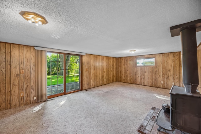 interior space featuring a wood stove, a wealth of natural light, carpet, and a textured ceiling