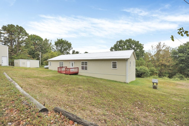 back of property with a shed, a lawn, and a wooden deck