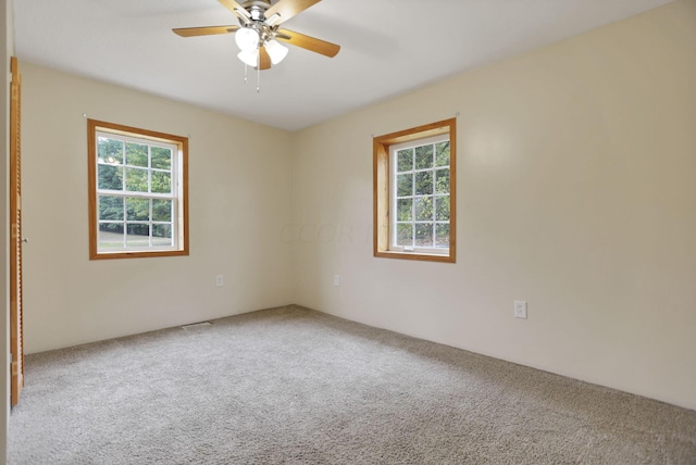 carpeted spare room with a wealth of natural light and ceiling fan