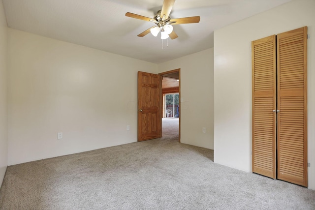 unfurnished bedroom featuring ceiling fan, a closet, and light carpet