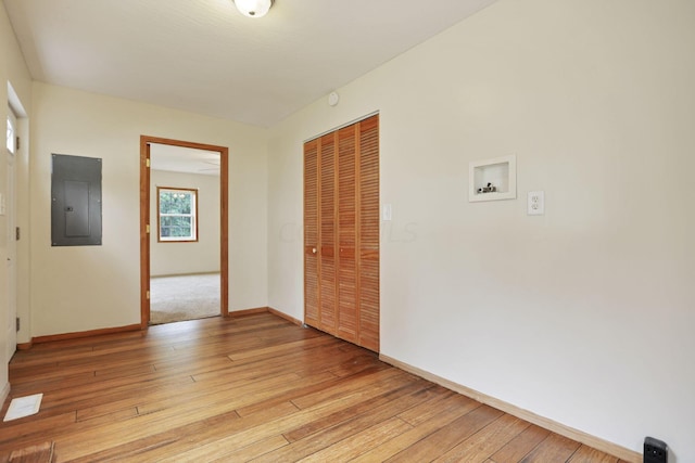 empty room featuring electric panel and light hardwood / wood-style floors