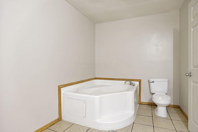 bathroom featuring tile patterned flooring, a bath, a textured ceiling, and toilet