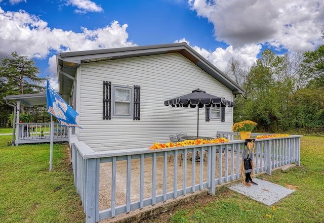 view of side of property featuring a lawn and a wooden deck