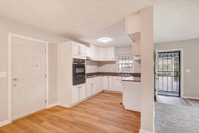 kitchen featuring stainless steel gas stovetop, white cabinets, oven, sink, and light wood-type flooring