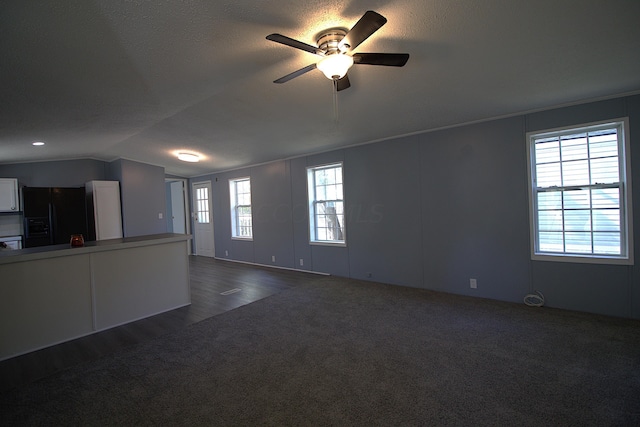 unfurnished living room with dark hardwood / wood-style flooring, vaulted ceiling, plenty of natural light, and ceiling fan