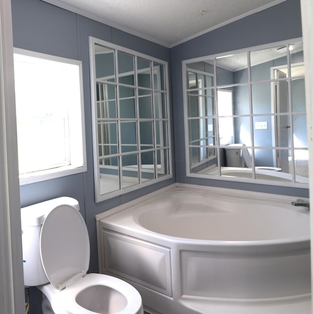 bathroom with a bath, a textured ceiling, and toilet