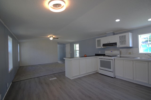 kitchen featuring white cabinets, sink, kitchen peninsula, white range oven, and wood-type flooring