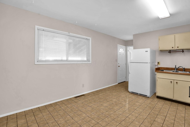 kitchen with cream cabinets, sink, and white refrigerator