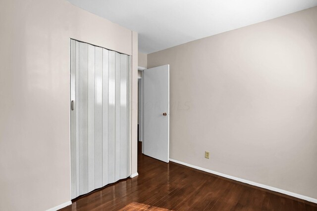 unfurnished bedroom featuring dark hardwood / wood-style flooring and a closet