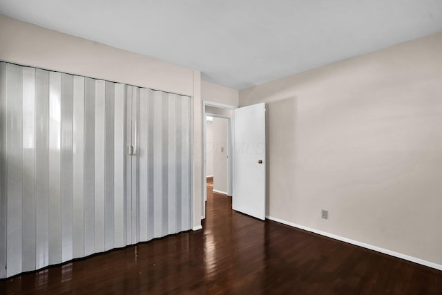 unfurnished bedroom featuring a closet and dark wood-type flooring