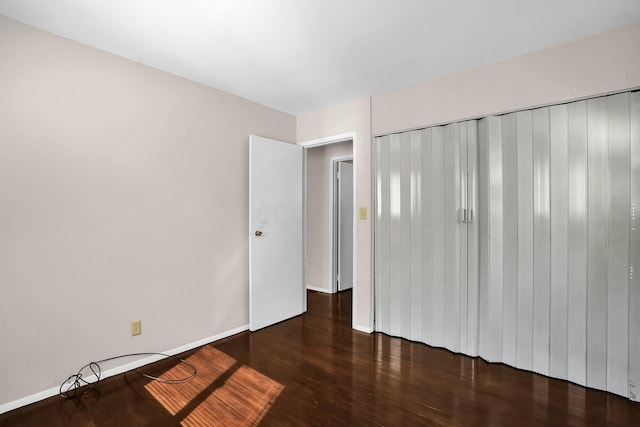 unfurnished bedroom with a closet and dark hardwood / wood-style floors