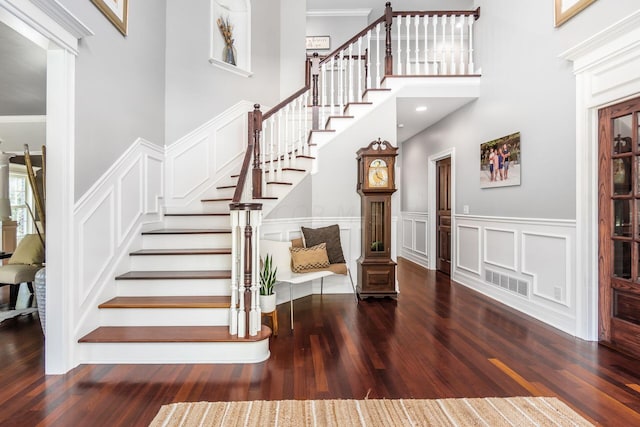 entryway with dark hardwood / wood-style flooring, ornamental molding, and a high ceiling