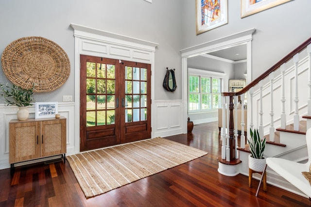 foyer entrance with dark hardwood / wood-style flooring, ornamental molding, and french doors