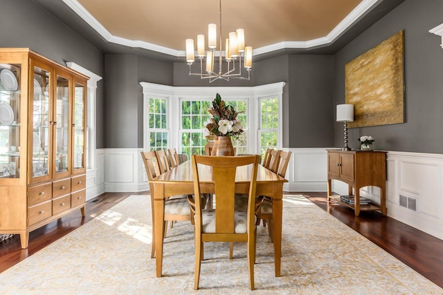 dining space with wood-type flooring, an inviting chandelier, and crown molding