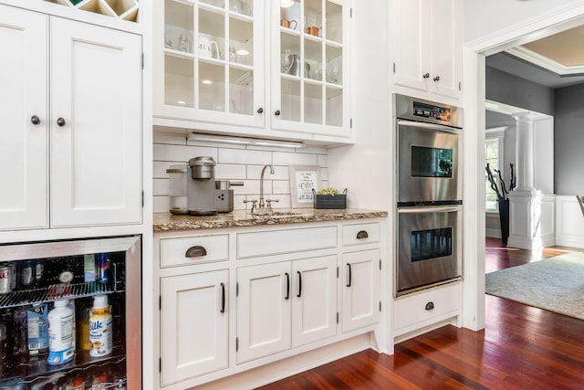 bar featuring light stone countertops, decorative columns, white cabinetry, and dark wood-type flooring