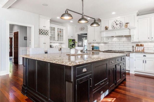 kitchen featuring stainless steel gas stovetop, a center island, dark wood-type flooring, white cabinets, and decorative light fixtures