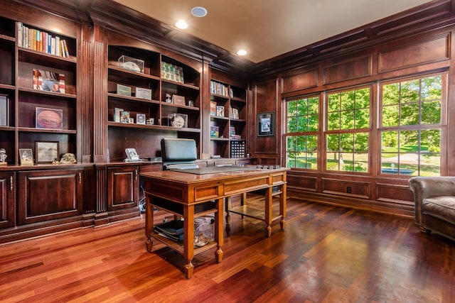 office area with wood-type flooring, built in shelves, crown molding, and wood walls