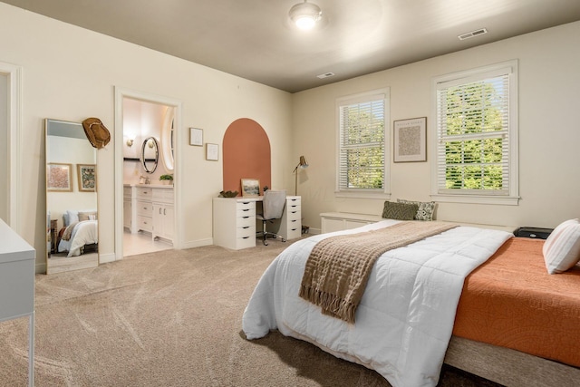 bedroom featuring light carpet and ensuite bath