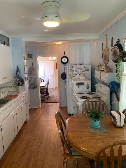 kitchen with white appliances, light hardwood / wood-style floors, white cabinetry, and crown molding