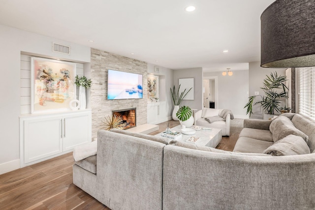 living room with wood-type flooring and a stone fireplace