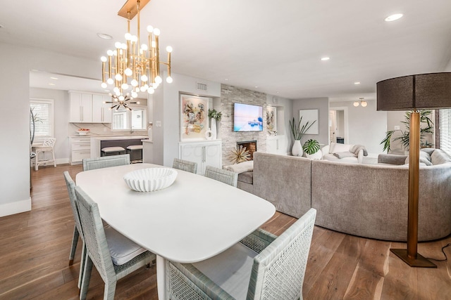 dining space featuring dark wood-type flooring, an inviting chandelier, and a fireplace