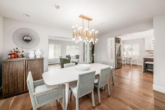 dining space featuring a baseboard radiator, a wealth of natural light, a notable chandelier, and light wood-type flooring