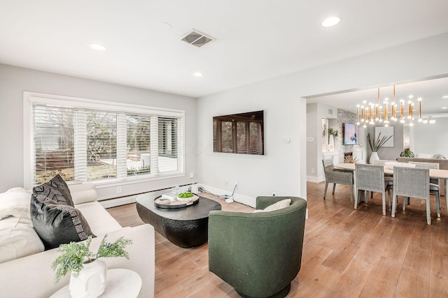 living room with a baseboard heating unit, a notable chandelier, and light wood-type flooring