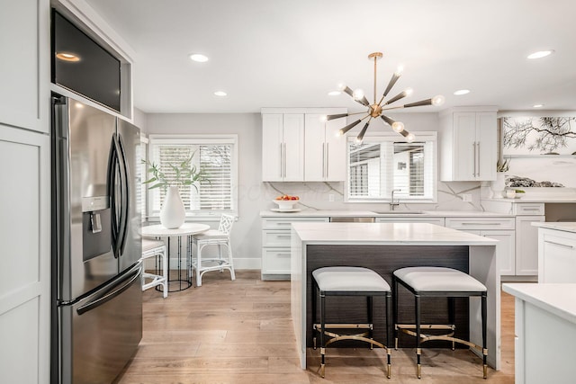 kitchen with stainless steel refrigerator with ice dispenser, sink, and white cabinets