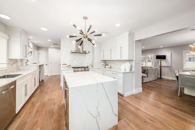 kitchen featuring light stone counters, a chandelier, a kitchen island, stainless steel appliances, and white cabinets