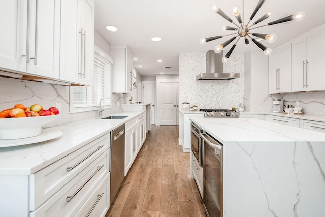 kitchen with sink, white cabinetry, light stone counters, stainless steel dishwasher, and wall chimney exhaust hood