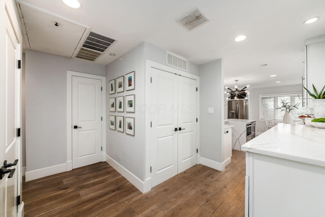 hallway with dark hardwood / wood-style flooring and a chandelier